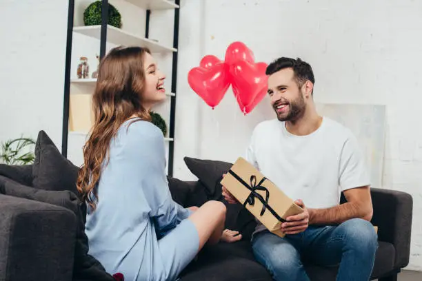 young man presenting gift box to girlfriend at valentines day