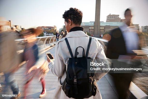 Back View Of Young Adult Woman Standing On Millennium Bridge London Using Smartphone Motion Blur Stock Photo - Download Image Now