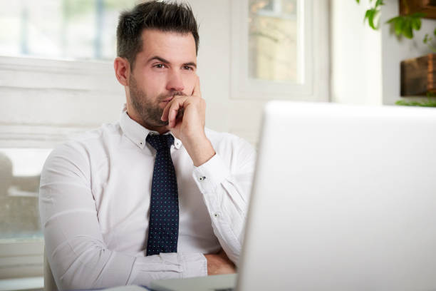 istock Businessman looking thoughfully while sitting behind his laptop in the office care 1095483284