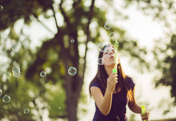 istock Young woman blowing bubbles in a park 1095490638