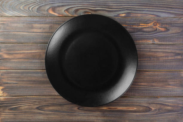 istock Directy above Empty black matte plate on wooden background 1095512618