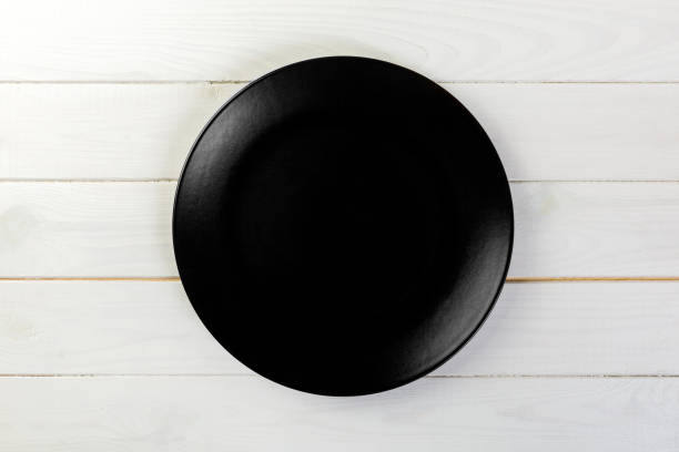istock Directy above Empty black matte dish for dinner on white wooden background 1095512628