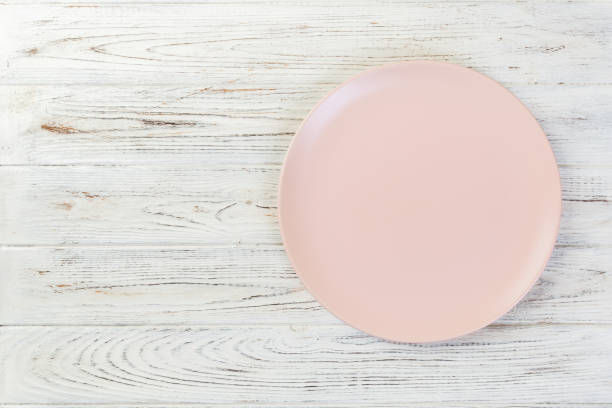 istock Directy above Empty pink matte plate on white wooden background with copy space 1095512672