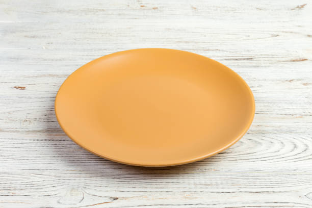 istock Perspective view. Empty yellow matte plate on white wooden background 1095512726
