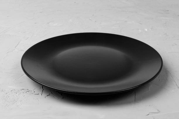 istock Top view of matte round empty dark dish on grey cement background copy space for you design. Perspective view 1095512770