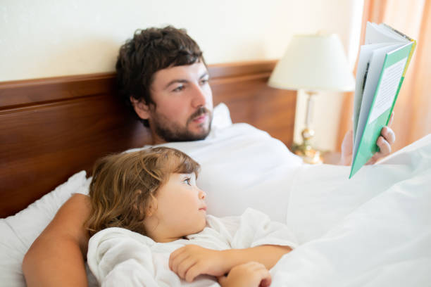 istock Bedtime Story. Dad and daughter read a book. 1095518172