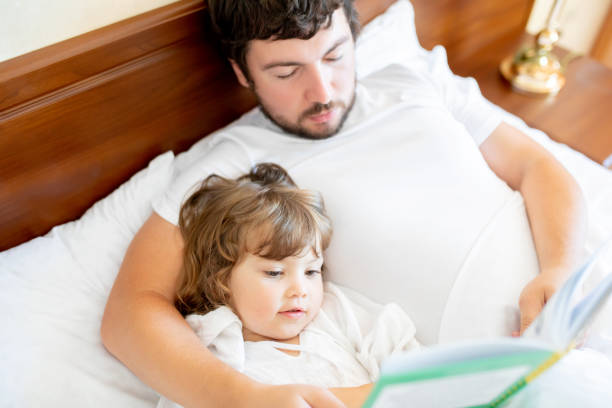 istock Bedtime Story. Dad and daughter read a book. 1095518232