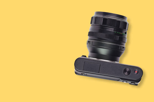 istock One professional digital black camera with lens on yellow table. Copy space for your text. Top view. Travel or video blogging concept 1095522640