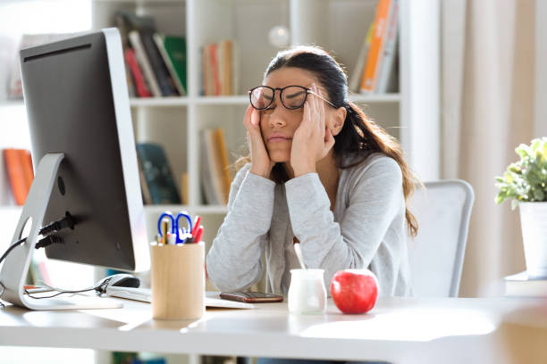 istock Tired young business woman having headache while working with computer in the office. 1095537270