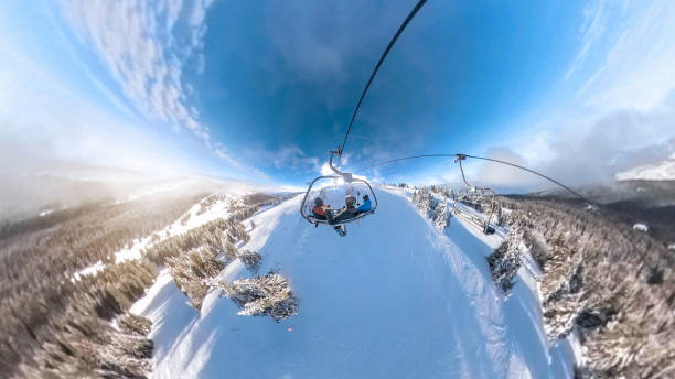 Group of friends skiers having a great time riding a cable car on a ropeway on a sunny day in the mountains.