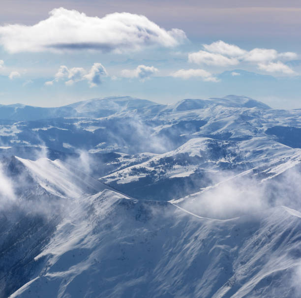 istock Snowy sunlight mountains in haze and cloudy sky 1095542012