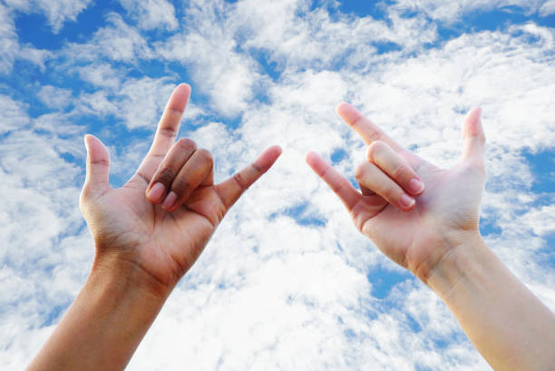 istock Two people show dumb language hand love with cloudy sky background 1095543590
