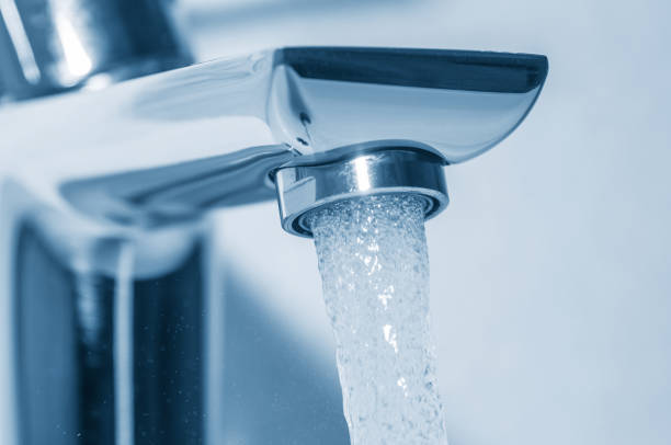 istock Flowing water from tap on blue background 1095546332