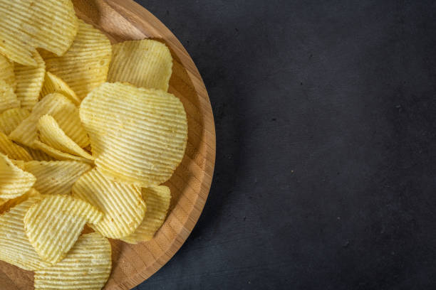 istock Plate of crispy potato chips on stone background 1095547098