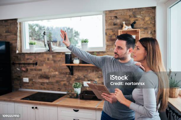 Couple Talking About Home Renovation Standing In The Kitchen And Discussing Apartment Renovation Ideas Stock Photo - Download Image Now
