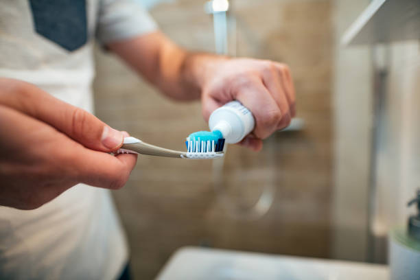 dental health care konzept. nahaufnahme des menschen drückt zahnpasta auf die zahnbürste. - toothpaste stock-fotos und bilder