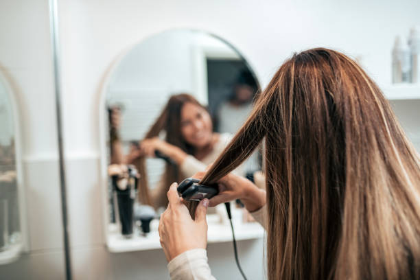 vista trasera del joven alisar el cabello con plancha. - straightener fotografías e imágenes de stock