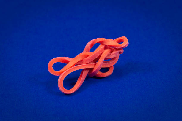 elastico rosso intrecciato su blu con spazio di copia - flexibility rubber rubber band tangled foto e immagini stock