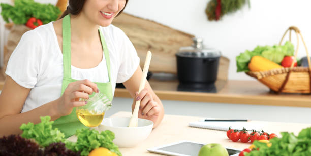 istock Beautiful Hispanic woman cooking in kitchen while using tablet computer and wooden spoon. Housewife found new recipe for dinner or breakfast. Healthy meal and householding concepts 1095568652