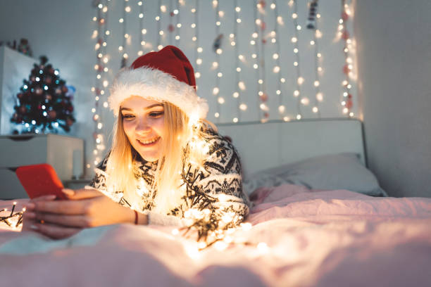 istock Smiling her lying on her bed with christmas lights in the background 1095570688