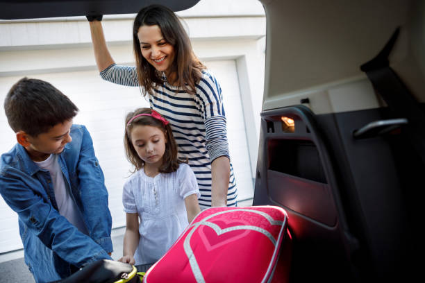 istock Mother and children loading school backpacks into car 1095579328