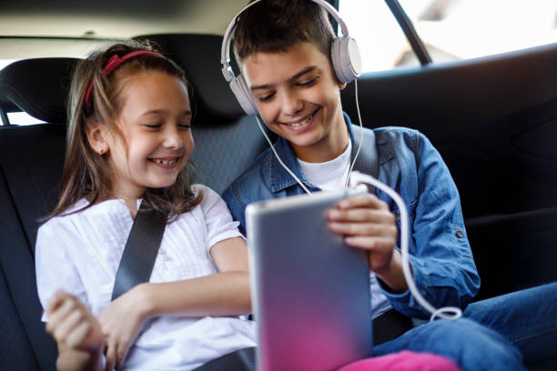 hermano y hermana que utilizan los medios sociales en el coche - seat belt audio fotografías e imágenes de stock