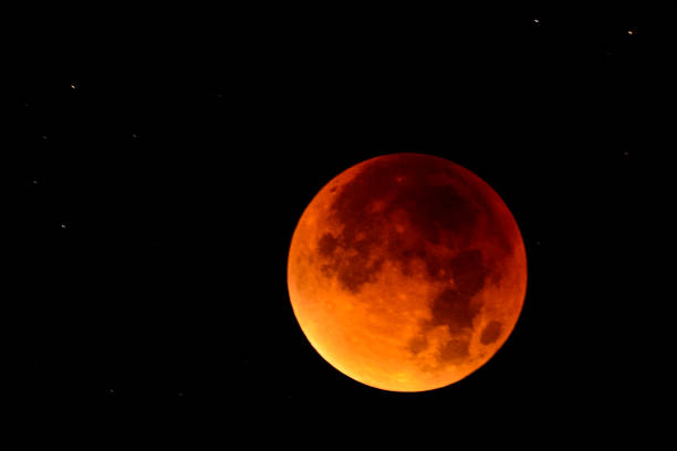 istock Full lunar eclipse in the dark night sky. The earth is blocking the light of the sun making the moon red 1095584374