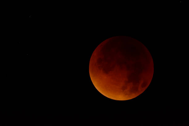 istock Full lunar eclipse in the dark night sky. The earth is blocking the light of the sun making the moon red 1095584412