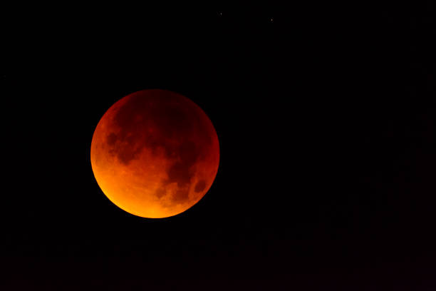 istock Full lunar eclipse in the dark night sky. The earth is blocking the light of the sun making the moon red 1095584504