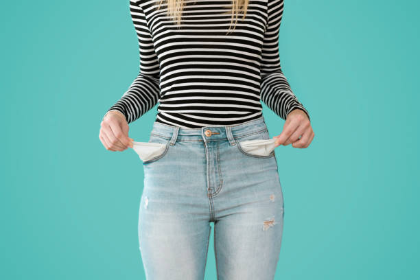 la giovane donna che mostra non ha nulla nelle tasche dei jeans su sfondo blu. - tasca foto e immagini stock
