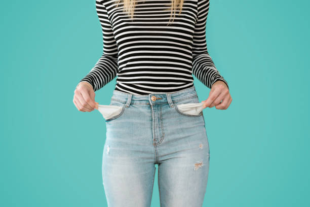 jovem mulher mostrando não tem nada nos bolsos jeans sobre fundo azul. - pocket - fotografias e filmes do acervo