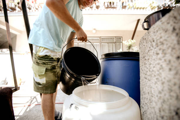 Pouring water from bucket Young man is filling a barrel with water from a bucket man wearing a barrel stock pictures, royalty-free photos & images