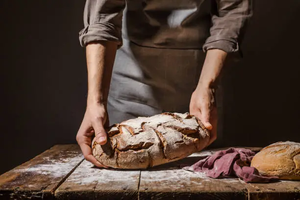 Baker of cooking chef putting fresh baked bread on table. Concept of cooking, successful businessman or start up. Closeup. Horizontal.