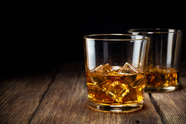 Two glass of whiskey with ice Two glass of whiskey with ice on wooden table. Copy space for text. cognac brandy photos stock pictures, royalty-free photos & images