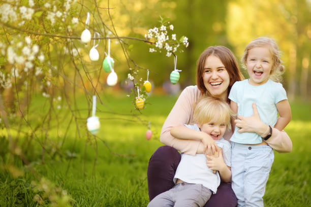 encantadores hijitos con su madre a la caza de pintaron huevos en parque de la primavera en el día de pascua - child discovery surprise playing fotografías e imágenes de stock