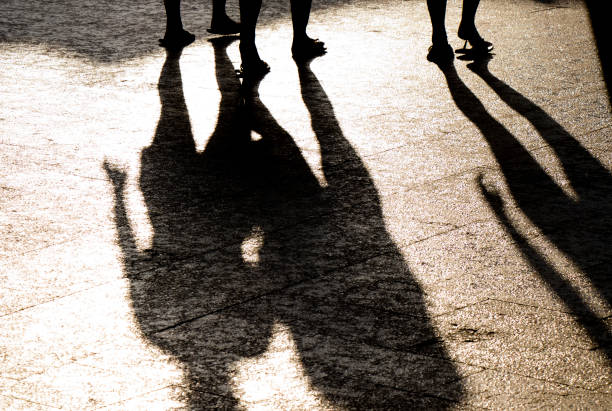 istock Blurry reflection shadow and silhouette of three people legs on summer bright sidewalk 1095623142