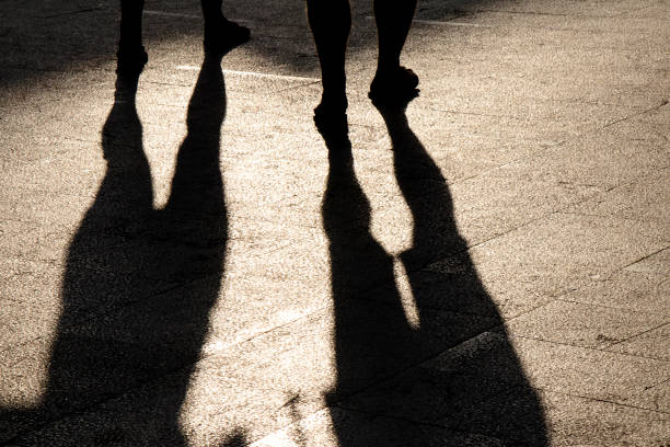 istock Blurry reflection shadow silhouette of two people legs on summer shiny sidewalk 1095623684