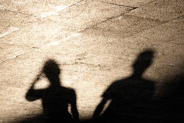 istock Blurry reflection shadow of two people on summer shiny sunny sidewalk 1095626282