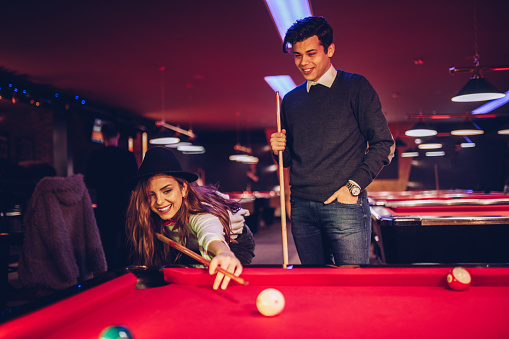 Young couple playing pool on the red pool tables.