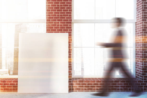 istock Man walking in brick room with poster 1095647016