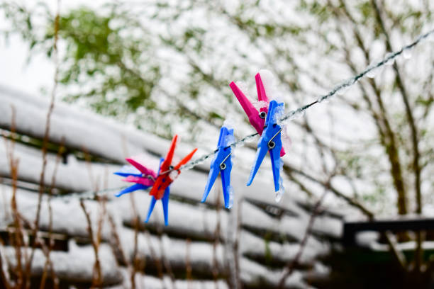 Icy colored clips for fastening laundry,frozen cord and blurred winter background.