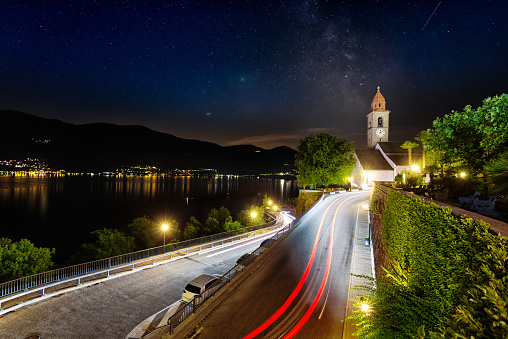 Long exposure photography from church in Ronco sopra Ascona in Switzerland with rear and front lights blurred from cars passing. You can recognize milky way in the sky.