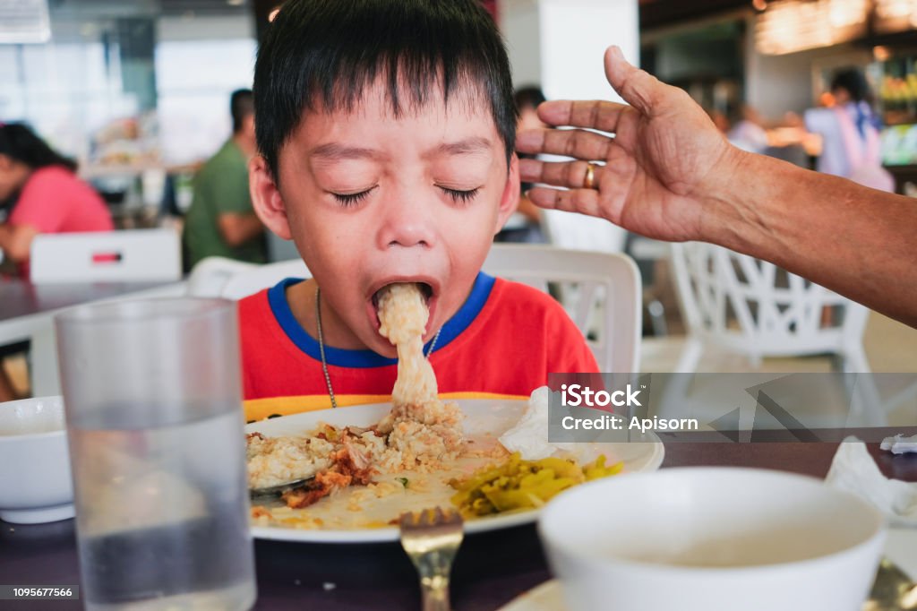 Garçon de vomir sur la plaque après avoir eu le repas du midi - Photo de Restaurant libre de droits