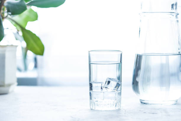 istock glass cup and carafe with water and ice on a white table 1095680608