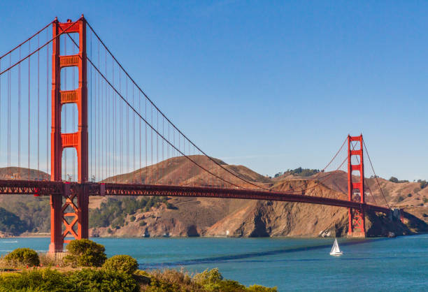 Golden Gate Bridge with sailboat sailing underneath, San Francisco, California, USA stock photo