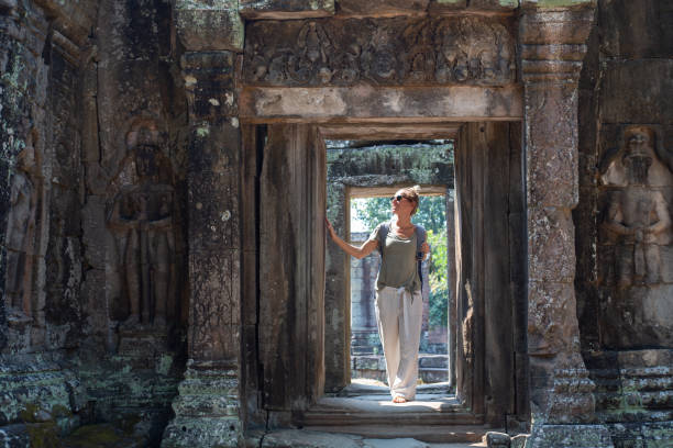 Young woman traveling in Cambodia visiting the temples of Angkor wat complex. People travel discovery Asia concept. Shot at sunset, one woman only, adventure and exploration in Siem Reap, Southeast Asia.