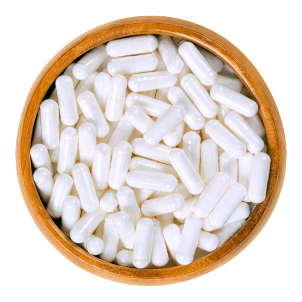 cápsulas de suplemento de comida branco em uma tigela de madeira sobre branco - capsule pill white nutritional supplement - fotografias e filmes do acervo