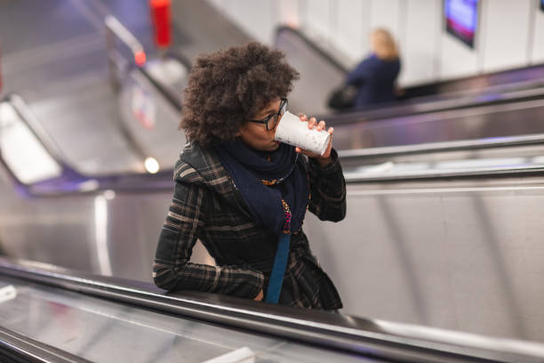 istock Beautiful young woman drinking coffee on escalator 1095698560