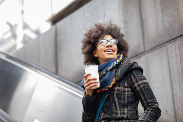 Happy young woman drinking coffee on escalator