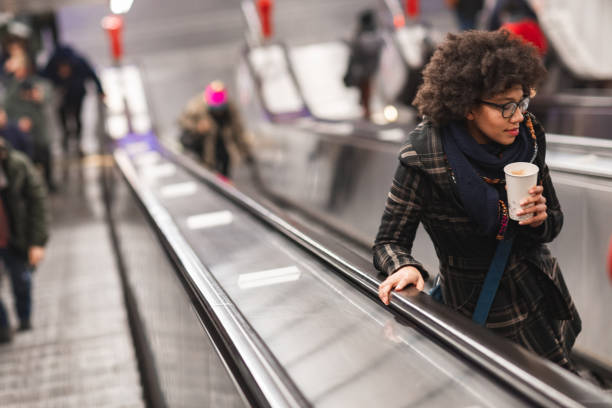 istock Beautiful young woman drinking coffee on escalator 1095700348